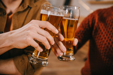 cropped view of men toasting glasses of beer