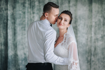 Beautiful newlyweds sitting in studio on sofa and hugging. The bride and groom on a blue sofa.