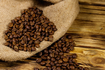 Roasted coffee beans on sackcloth on wooden table