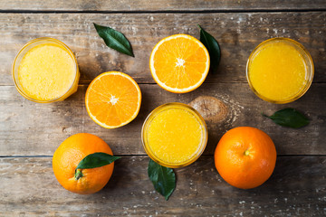 Top view of freshly pressed orange juice and oranges on wooden table