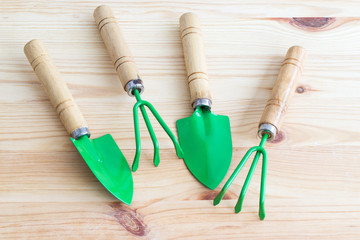 Gardening Tools. Conceptual image of garden tools with place for text. Rake, shovel and weeding knife on a light wooden background. View from above.