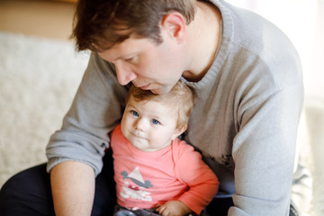 Happy proud young father having fun with baby daughter, family portrait together. Dad with baby girl, love. Man playing with little child at home.