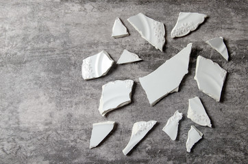broken vintage porcelain plate on old grey background. smithers. Copy space