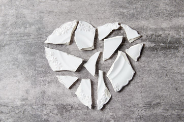 Broken heart concept. Divorse, quarrel. broken vintage porcelain plate on old grey background....