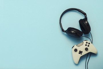Headphones and gamepad on a blue background. . Concept of computer games, entertainment, gaming,...