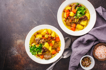 Traditional eintopf soup with meat, beans and vegetables in a white plate, copy space.