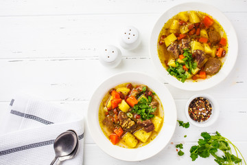 Traditional eintopf soup with meat, beans and vegetables in a white plate, copy space, white...