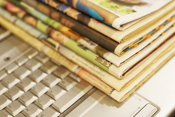Newspapers and laptop. Pile of daily papers with news on the computer. Pages with headlines,...