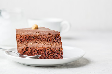 Piece of chocolate cake on white plate, white background. Vegan dessert, plant based food concept.