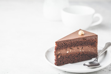 Piece of chocolate cake on white plate, white background. Vegan dessert, plant based food concept.