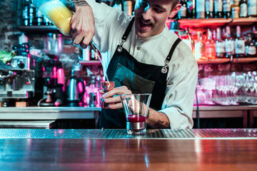 Expert barman is making cocktail at night club or bar. Glass of fiery cocktail on the bar counter...