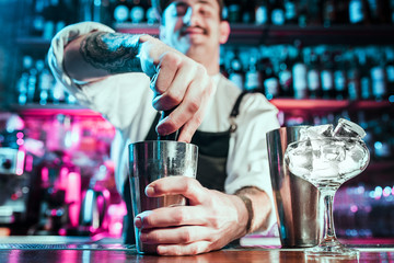 Expert barman is making cocktail at night club or bar. Glass of fiery cocktail on the bar counter against the background of bartenders hands with fire. Barman day concept