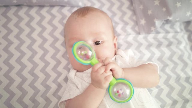 Portrait of cute baby boy playing toy. Cute child playing with rattle on bed