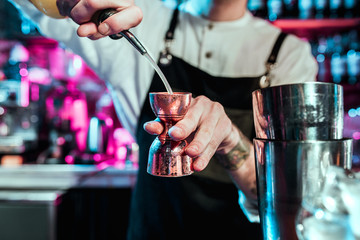 Expert barman is making cocktail at night club or bar. Glass of fiery cocktail on the bar counter against the background of bartenders hands with fire. Barman day concept