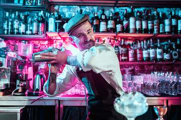 Expert barman is making cocktail at night club or bar. Glass of fiery cocktail on the bar counter against the background of bartenders hands with fire. Barman day concept