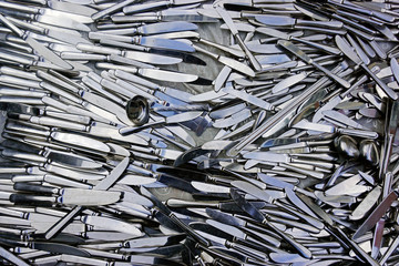 Pile of silver color knives and a spoon as a background