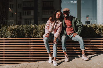 Cheerful lover couple sit on wooden balustrade