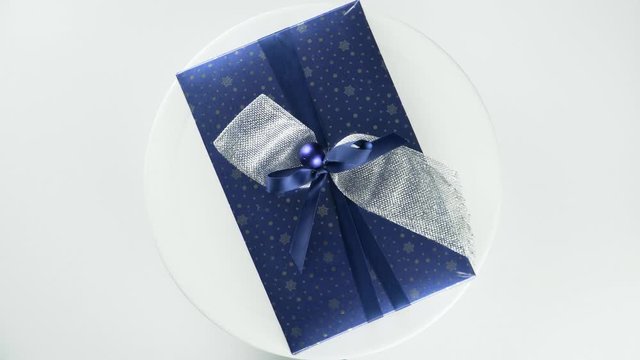 A blue gift tied with a ribbon on a rotating platform