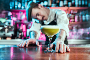 Expert barman is making cocktail at night club or bar. Glass of fiery cocktail on the bar counter against the background of bartenders hands with fire. Barman day concept - obrazy, fototapety, plakaty