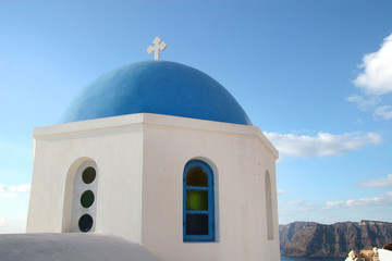 Fototapeta na wymiar Traditional white church with a Blue dome, perched on the side of the cliff, Oia, Santorini, Greece.