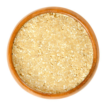 Homemade white tahini with sesame seeds in wooden bowl. Condiment made of ground husked sesame seeds. Dip or major ingredient in hummus, baba ghanoush or halva. Food photo closeup on white background.
