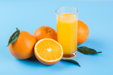 Orange juice and fresh oranges on blue background