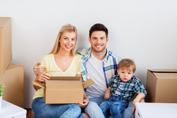 mortgage, people, family and real estate concept - happy mother, father and little son with cardboard boxes moving to new home