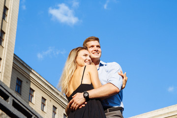 couple in love embraces against the background of the building and the sky, smiling. date,love Valentine's Day