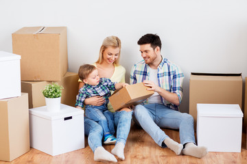Fototapeta na wymiar mortgage, people, family and real estate concept - happy mother, father and little son with cardboard boxes moving to new home