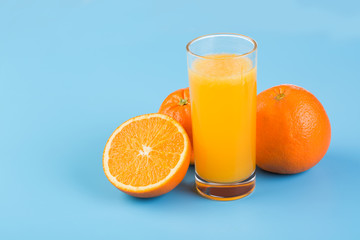 Orange juice and fresh oranges on blue background