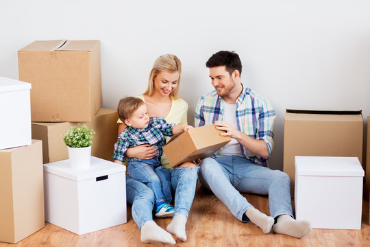 mortgage, people, family and real estate concept - happy mother, father and little son with cardboard boxes moving to new home