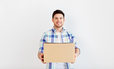 people and moving to new place concept - happy man holding cardboard box