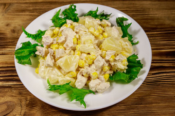 Festive salad with chicken breast, sweet corn, canned pineapple and mayonnaise on wooden table