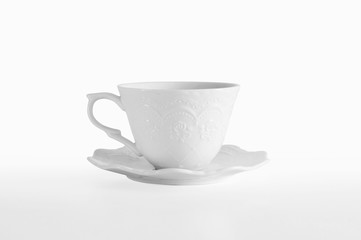 Beautiful elegant white porcelain cup with a saucer with a romantic floral ornament on white...