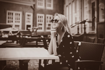 Young girl in black dress and sunglasses in Amsterdam cafe. Holland, Netherlands Image in sepia color style