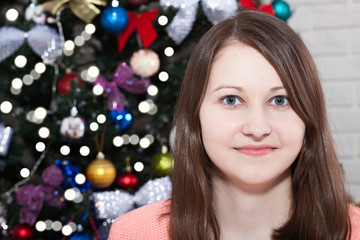 Fototapeta na wymiar Happy young lady with gifts by the fireplace near Christmas tree. New year concept.