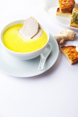 Chicken cream soup with a curry and pieces of chicken meat. On a white background. Toasts with garlic and cheese. Close up. Selective focus.