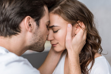 close up of happy man kissing nose of girlfriend