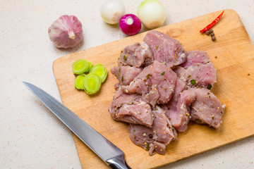 Raw pork kebab on wooden cutting board.