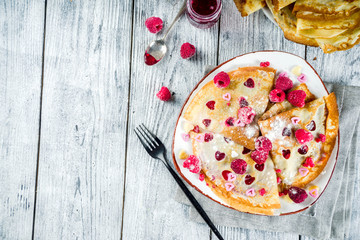 Idea for Valentine's Day surprise gift. Cute pancakes crepes with berry sauce and heart shaped cutouts. Romantic valentine breakfast. On wooden table, with fresh raspberries. Copy space