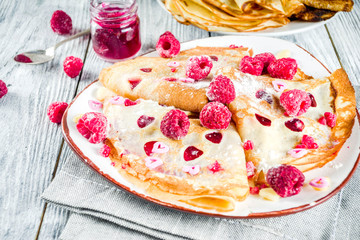 Idea for Valentine's Day surprise gift. Cute pancakes crepes with berry sauce and heart shaped cutouts. Romantic valentine breakfast. On wooden table, with fresh raspberries. Copy space