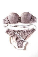 Set of elegant glamorous lacy women&rsquo;s lingerie with measuring tape, on white background. Slimming and beauty concept