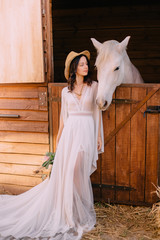 young boho style bride is stroking white horse © MZaitsev