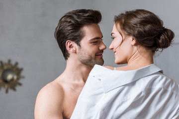 adult man gently taking off shirt from girl and looking into eyes