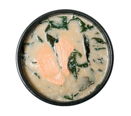 Creamy suimono in a black bowl. Soup with salmon and seaweed.