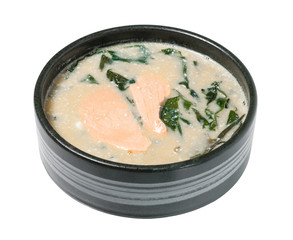 Soup with salmon and seaweed in a black bowl.
