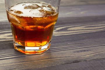 whiskey with ice cubes on wooden background