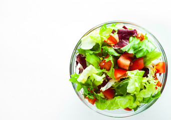 various fresh mix salad leaves with tomato in glass bowl isolated on white background.