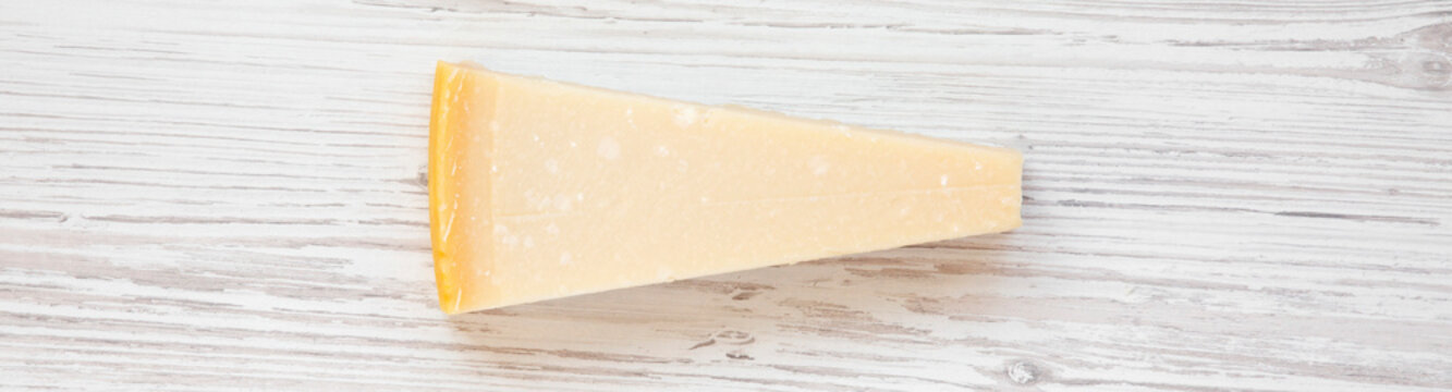 Piece Of Parmesan Cheese On White Wooden Surface, Top View. Flat Lay. From Above, Overhead.