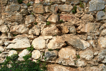 Old City walls. Stone Texture. Wall texture of ancient old brick stone. Outdoor exterior castle facade with destroyed uneven pattern of shabby rock. Grunge surface. Wall of the fortress